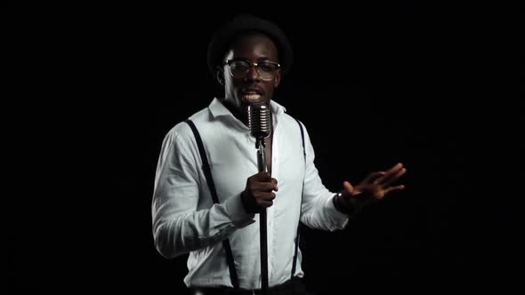 African American with Glasses Singing and Dancing To the Music From the Microphone. Black Background