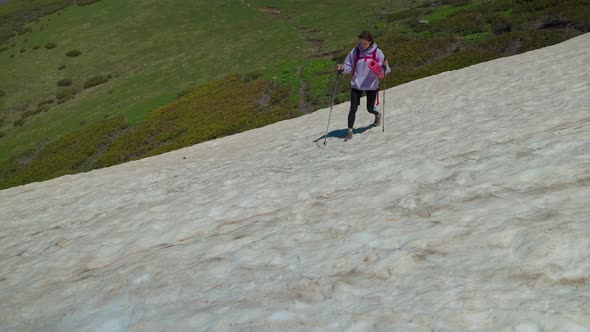 Girl Hiker Walking Carefully on Snowy Hillside