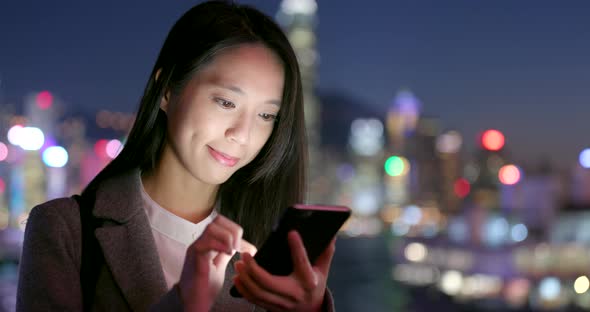 Businesswoman use of cellphone in city at night