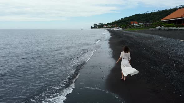 Woman Walks Along the Black Sand Beach