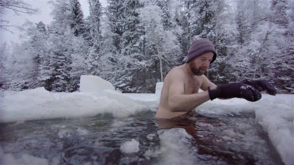 A handsome bearded ice bather sits into a large ice bath for his daily routine