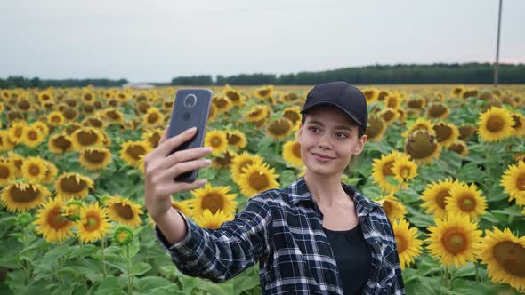 Countryside Farmer Female Standing in a Field of Sunflowers and Takes Selfie Pictures on a