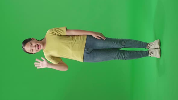 Full Body Of Happy Young Asian Kid Girl Waving Hand And Say Bye Bye While Standing On Green Screen