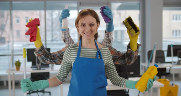 Multiarmed Housemaid Holding Cleaning Equipment and Smiling at Camera in Office