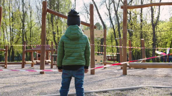 Child Standing Near a Closed Playground