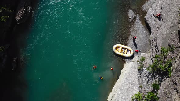 people swimming in choppy turquoise waters of Vjosa river after rafting. Overhead pull back reveal