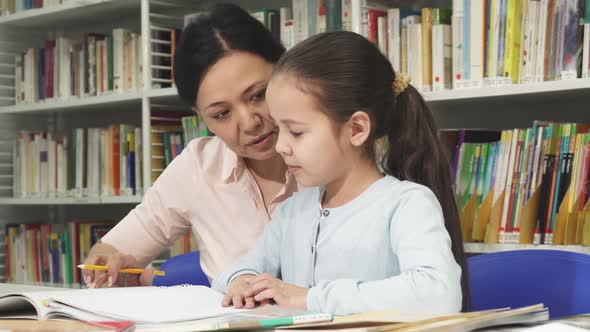 Cute Little Girl Doing Homework with Her Mother