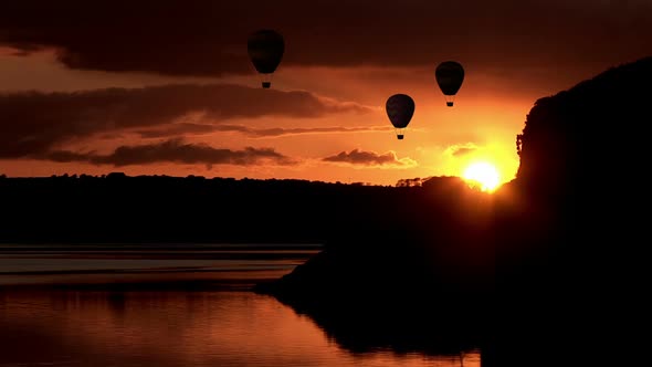 Hot air balloons flying over lake during sunset