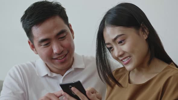 Asian couple using mobile phone browsing social media communication.