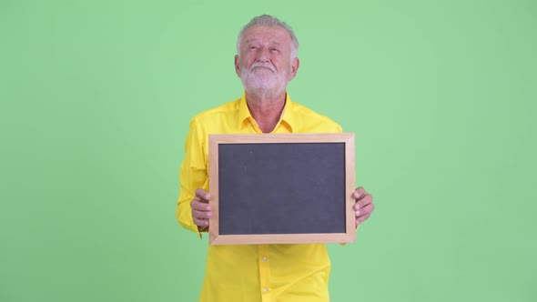 Happy Senior Bearded Businessman Thinking While Holding Blackboard