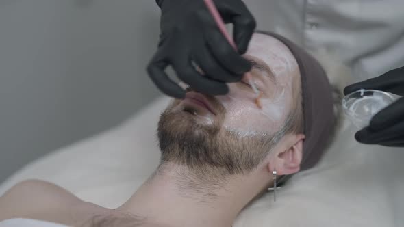 Unrecognizable Beauty Therapist Using Brush Applying White Enzyme Peel on Face Skin of Male Client