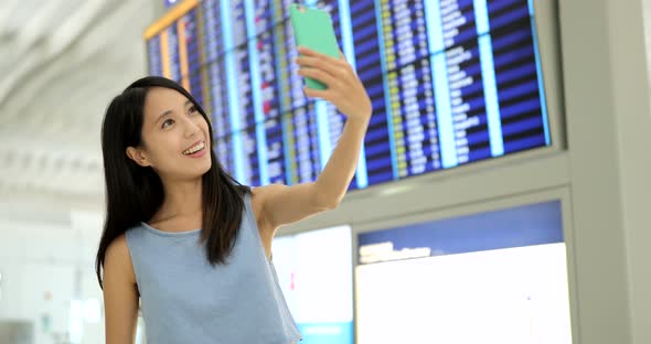 Woman Taking Selfie with Cellphone at Airport 