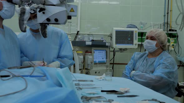 Surgeons Perform a Complex Operation Using a Microscope