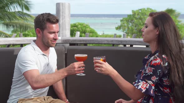 A man and woman couple have a drink on a tropical island