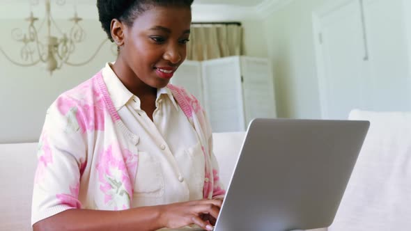 Woman sitting on sofa and using laptop in living room