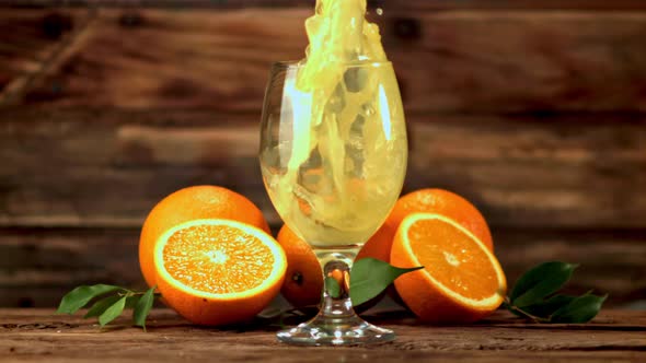 Super Slow Motion Orange Juice Pours Into a Glass of Spray
