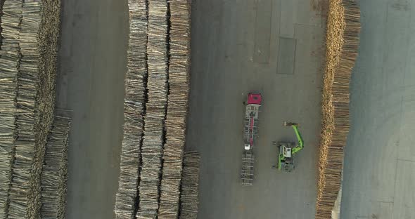 Log Piles in Wood Terminal Crane Unloading Timber From Logging Truck Aerial View