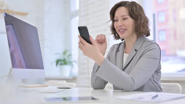 Creative Old Woman Celebrating Success on Smartphone