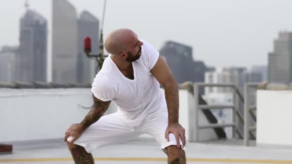 Tattooed Fellow Stretches Upper Body By Twisting It From Left To Right