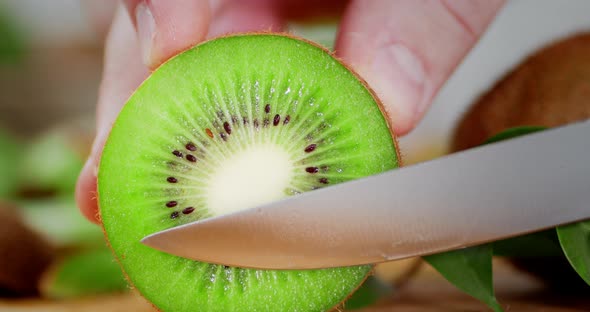 Male Hand with a Knife Holds a Slice of Fresh Kiwi. 