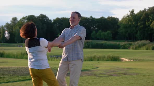 Happy Mature Couple Holding Hands Spinning Green Grass