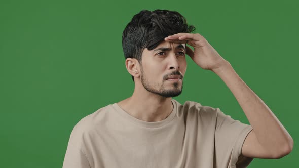 Puzzled Nervous Guy Arab Hispanic Man Posing on Green Background Put Head to Forehead Looking Around