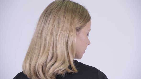 Closeup Rear View of Young Happy Blonde Woman Smiling and Looking Back