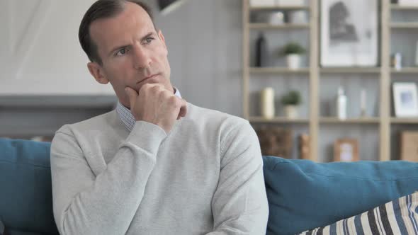 Middle Aged Man Thinking New Idea While Sitting on Couch in Creative Office