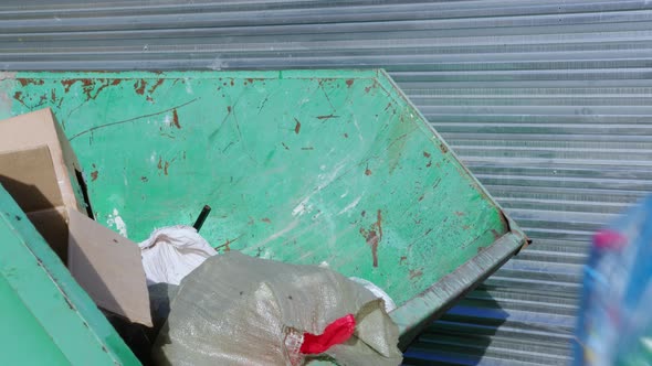Person Throws Bag of Garbage Into Dumpster