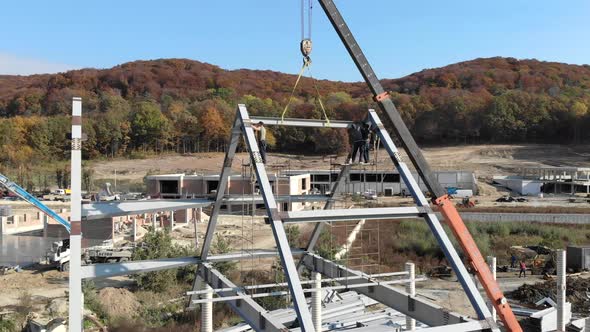 Aerial Shot Installation of a Roof and a Framework From a Metal Construction. Workers Mount the Roof