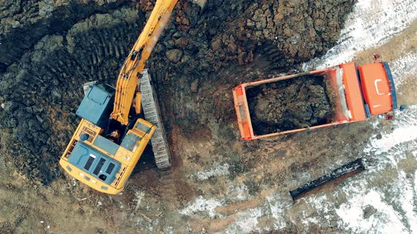 Construction Excavator Work at the Industrial Quarry. A Machine with Bucket Loads a Truck at a