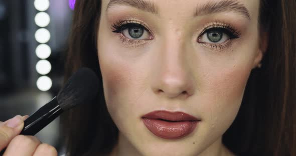 Closeup of Girl with Perfect Nude Makeup and Makeup Artist