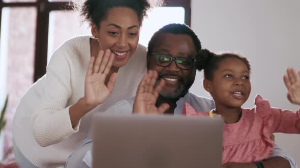 Smiling family talking by video call on laptop