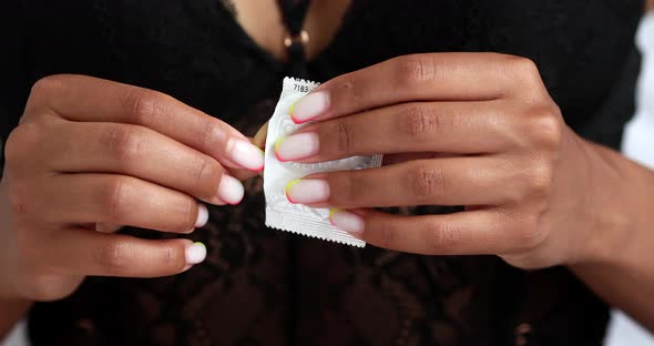 Young black woman holding condom in hand.