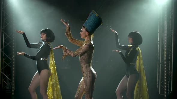 The Actress, Dressed As the Queen of Ancient Egypt, Dances with Two Women in a Dark Studio