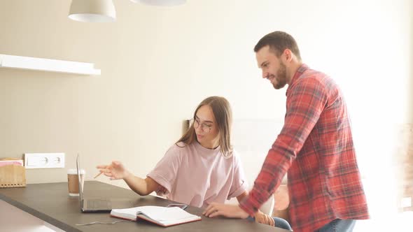 Young Couple Expresses Positive Emotions Looking at Laptop with Attractive Smile