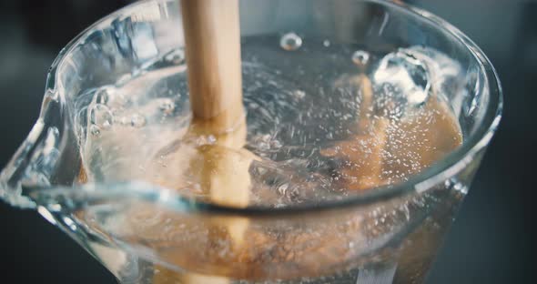 Powder for iced tea is placed in a glass carafe and stirred