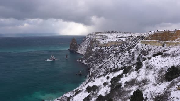 Snow Covered Rocky Cliffs Over Sea