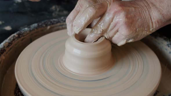 Close-up of Old Man's Hands Working with Wet Clay on Throwing Wheel Shaping Vase