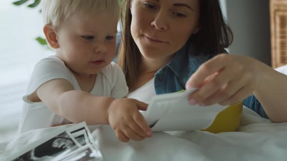 Woman and her little son browsing pregnant photographies on bed. Shot with RED helium camera in 8K 