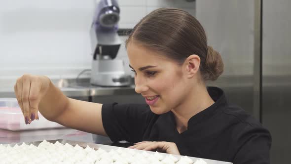 Beautiful Female Pastry Chef Decorating Meringues with Coconut Flakes