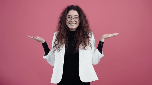 The Smiling Young Woman with Curly Hair Holds Her Hands to the Side and Says Look Like That Smiling