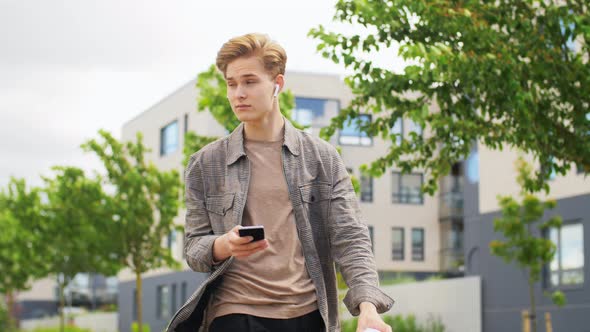 Young Man with Smartphone Drinking Coffee in City