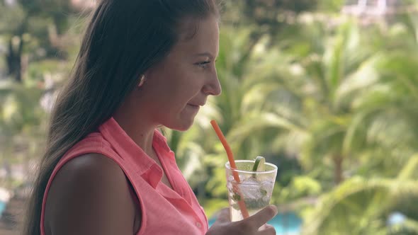 Girl Stands on Balcony with Mojito and Looks Away at Palms