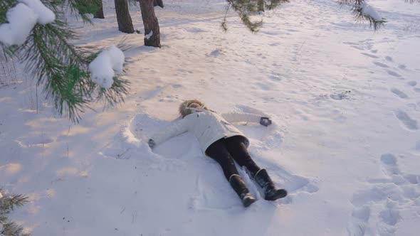 The Girl Makes a Snow Angel in a Clearing in the Forest a Shot From Above