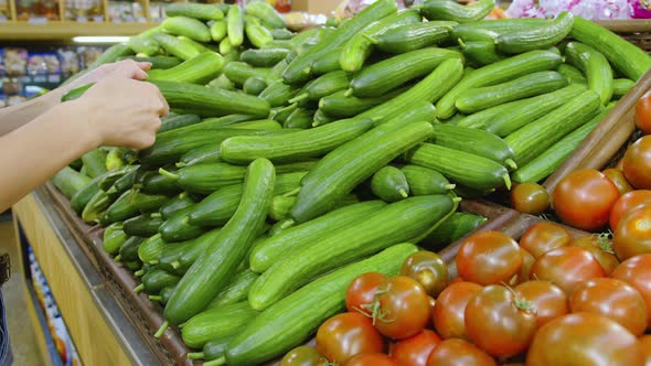 A Woman is Buying Cucumbers at the Supermarket