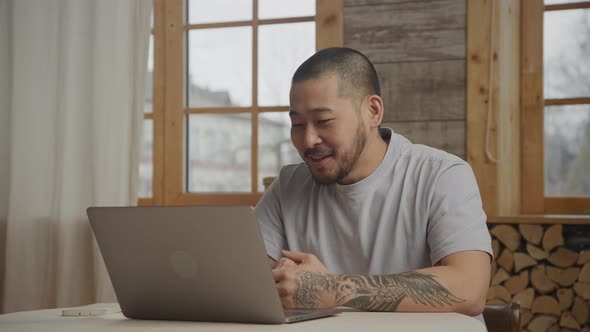 Asian Man on a Video Call Using Laptop Indoors