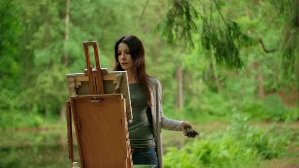 Middle View of a Beautiful Brunette Female Painting a Picture in a Park