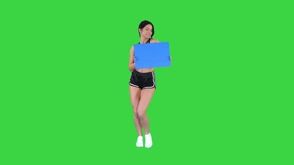 Charming Girl Holding Empty Board and Dancing on a Green Screen, Chroma Key.