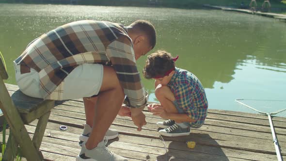 Family of Fishermen Putting Baits on Hooks to Fish with Fishing Rod on Pond